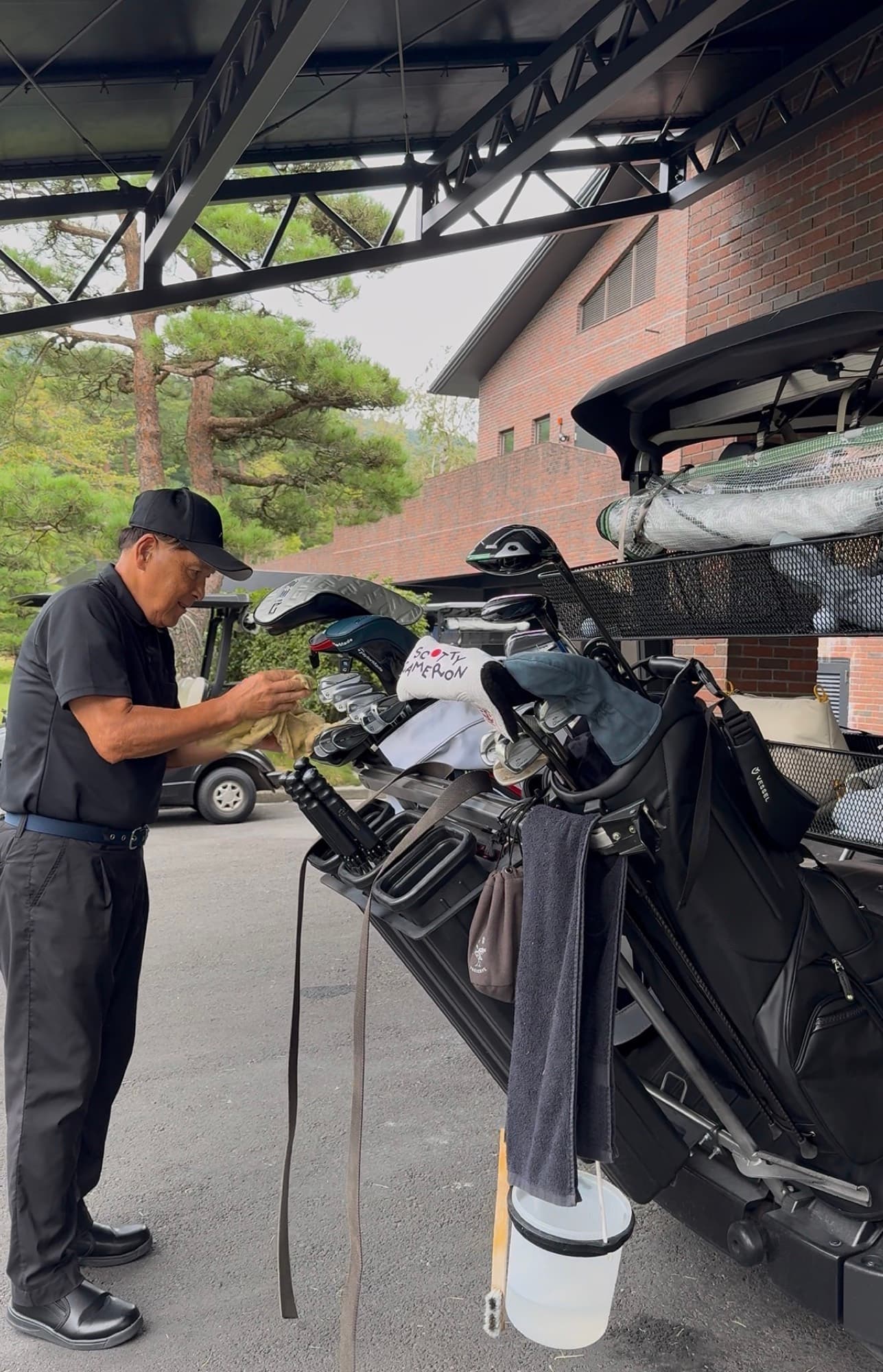 An attendant wiping down the clubs at the bag drop right after the round