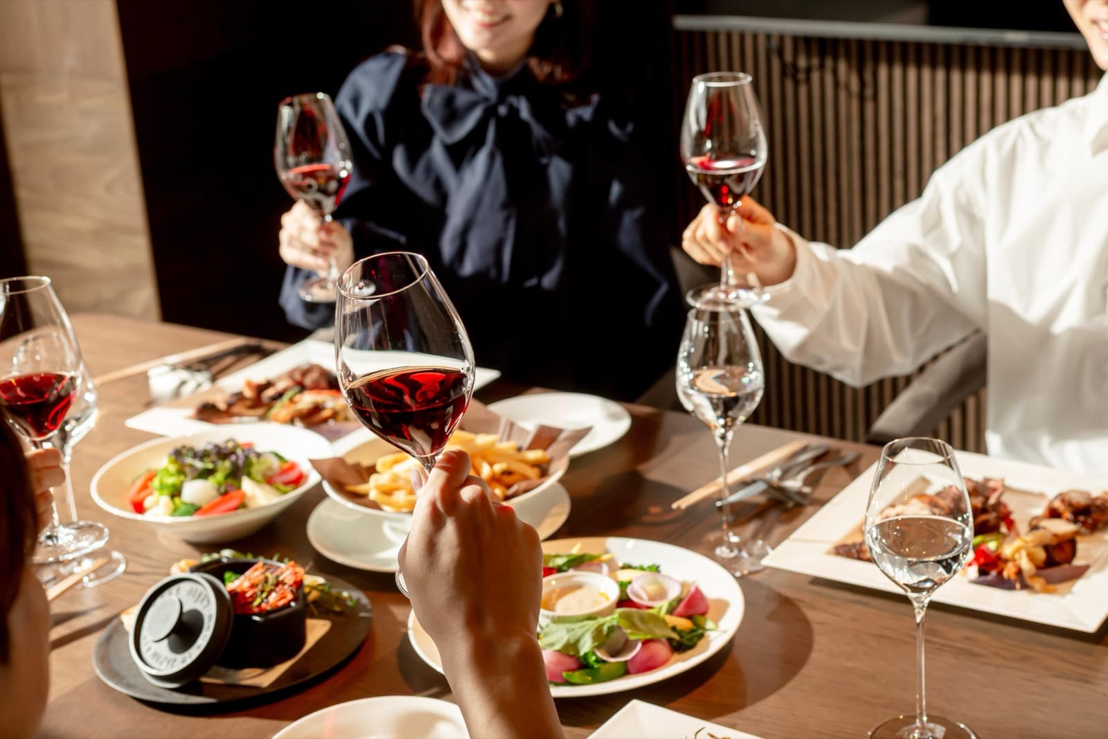 Guests raising wine glasses over the BBQ dinner table