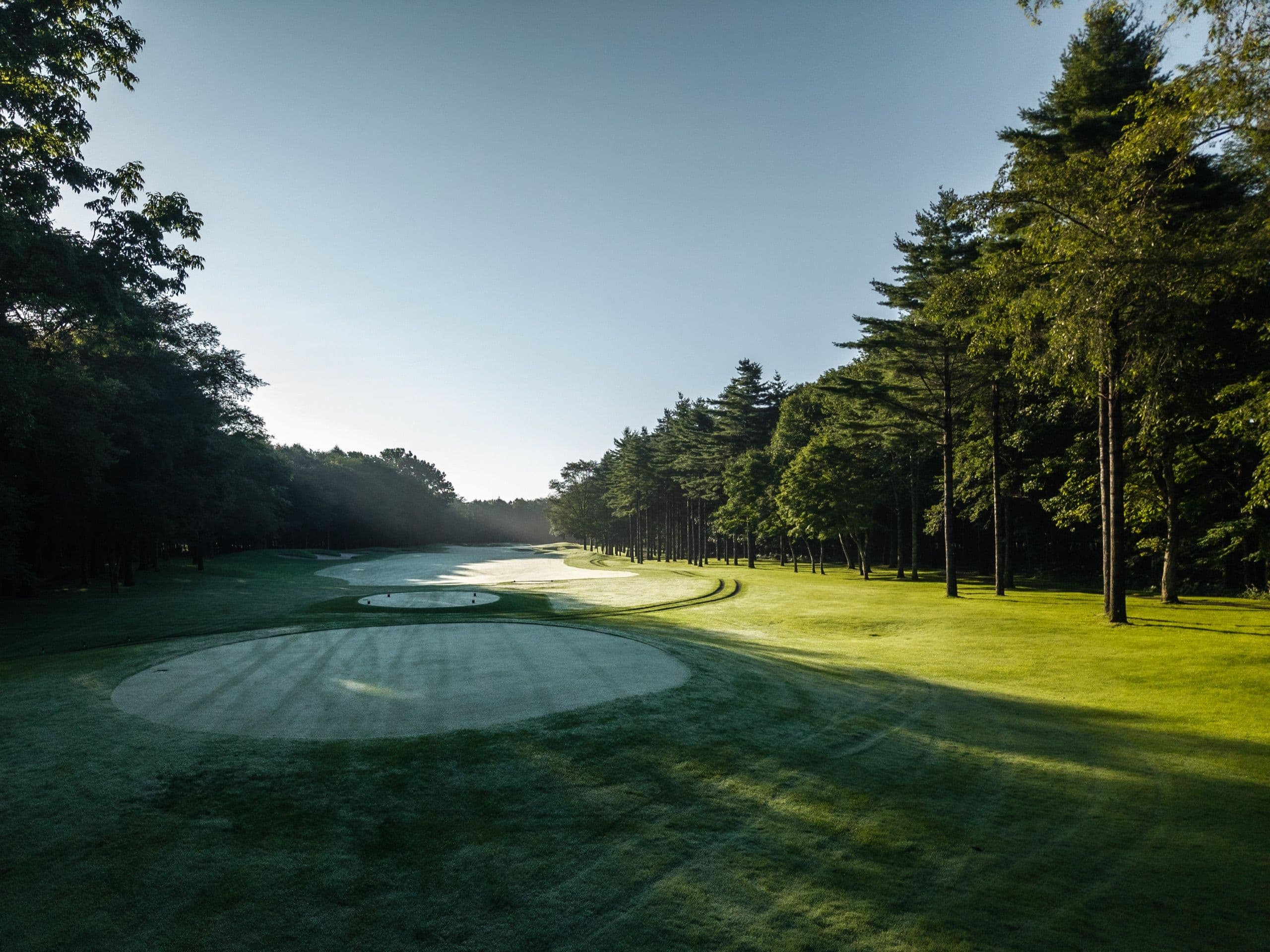 A tree-lined fairway at first light on a Preserve Golf Japan course.