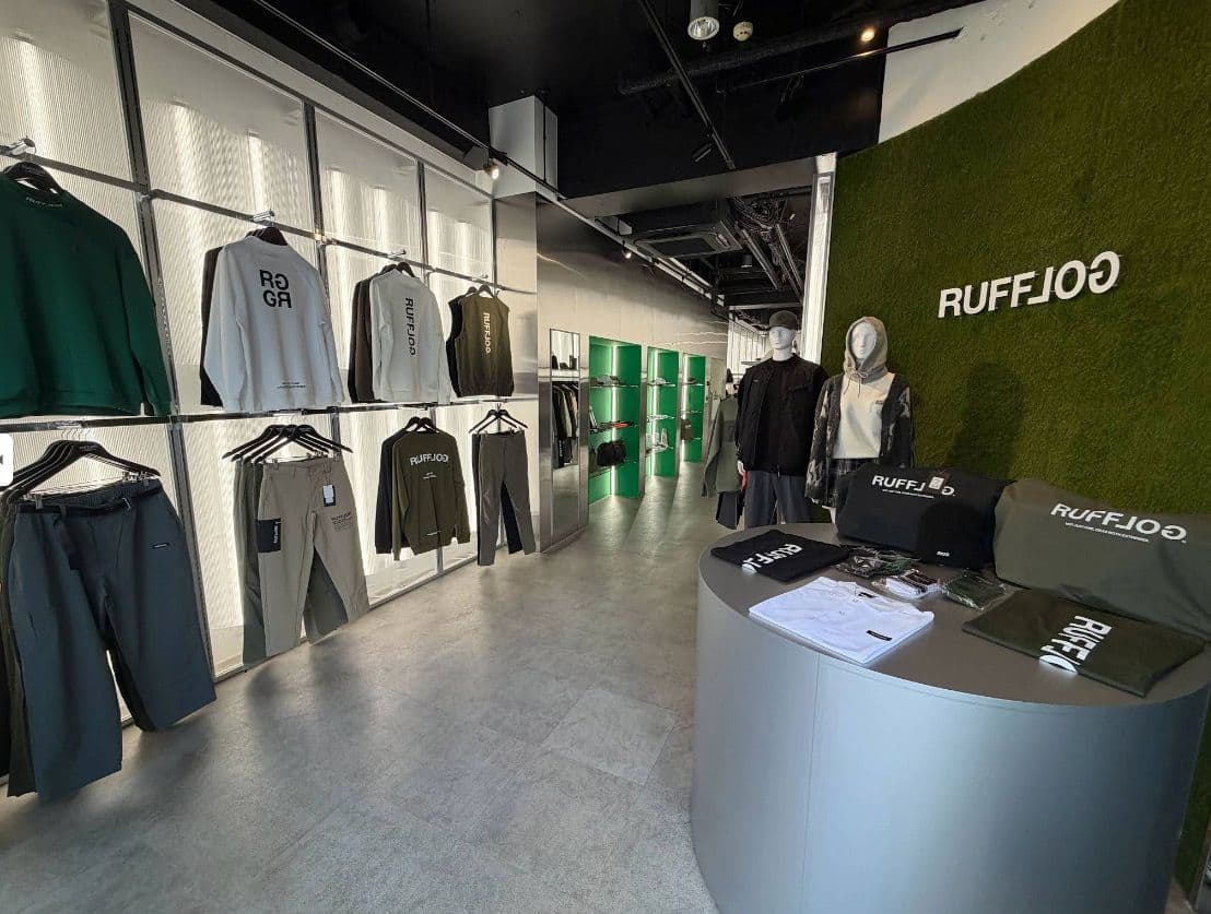 Inside RUFFLOG Osaka — apparel racks and the moss-green logo wall